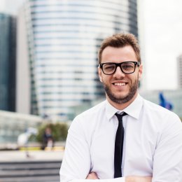 Ein Sales-Manager steht vor einem Bürokomplex