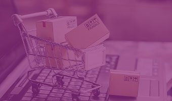 Kleiner Einkaufswagen ist voll mit Paketen und steht auf einer Laptoptastatur