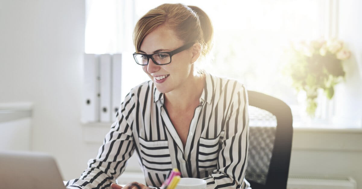 Eine Studentin sitzt an ihrem Schreibtisch und blickt auf ihren Laptop.