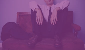 Geschäftsmann mit hochgezogenen Knien auf einem Sessel