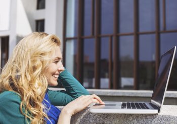 Eine Studentin betrachtet lachend etwas auf ihrem Laptop.
